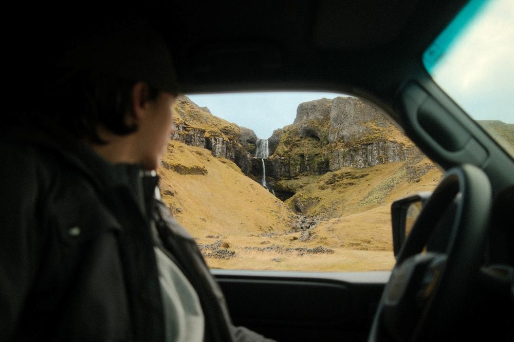 Iceland waterfall car rental. Driving looking at a waterfall in Iceland from the rental car window.