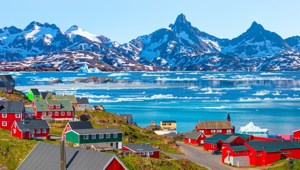 Small town in Greenland. Greenland town with colorful houses and icebergs floating in the blue fjord.