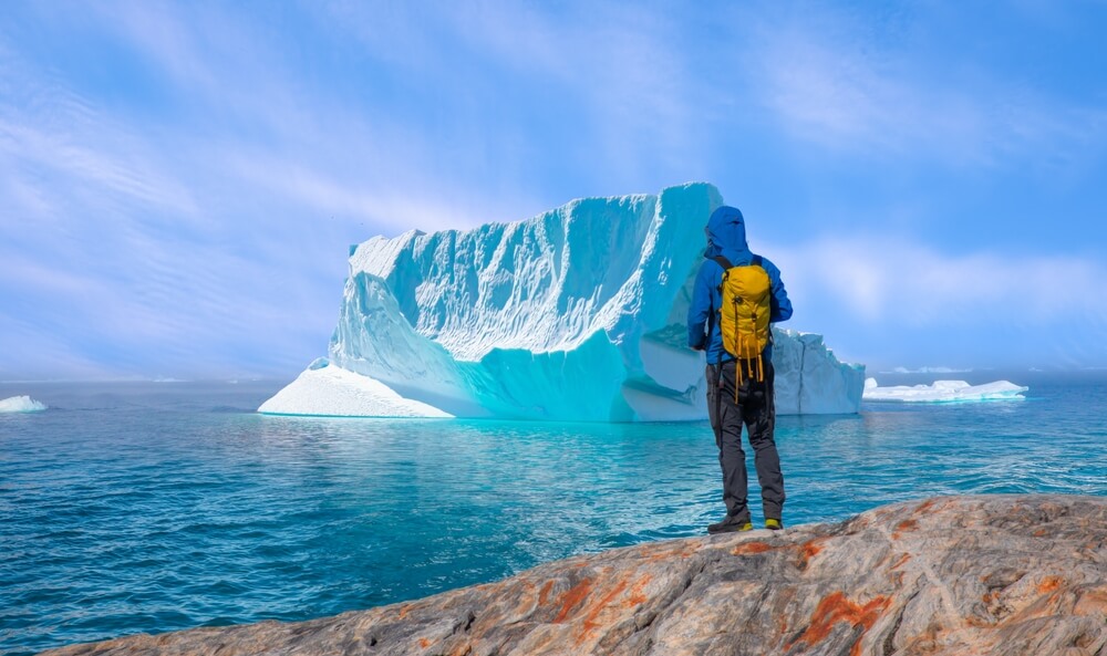 Greenland iceberg. Traveller looking at an iceberg of the coast of Greenland.