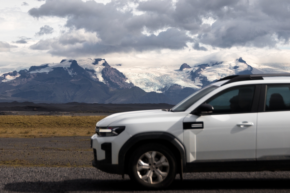 4x4 rental and glacier in Iceland. White Dacia Duster rental car 4x4 and Eyjafjallajökull in the background.
