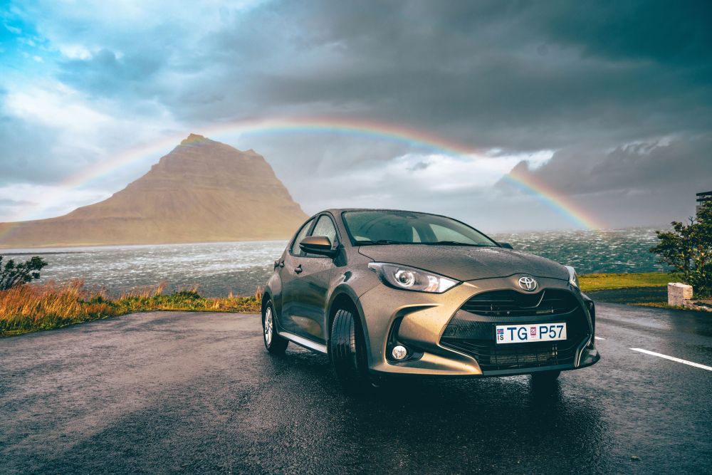 Iceland spring. Toyota Yaris under a rainbow at Kirkjufell in spring.
