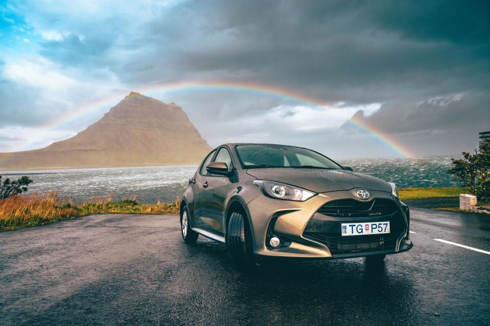 Small car in front of Kirkjufell mountain and rainbow at snæfellsnes Iceland.