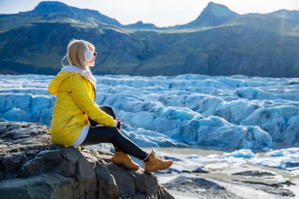 Jökulsárlón. Women in a yellow jacket sitting atJökulsárlon