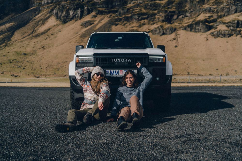 Travel partners in Iceland. Two women sitting in front of a Toyota Land Cruiser.