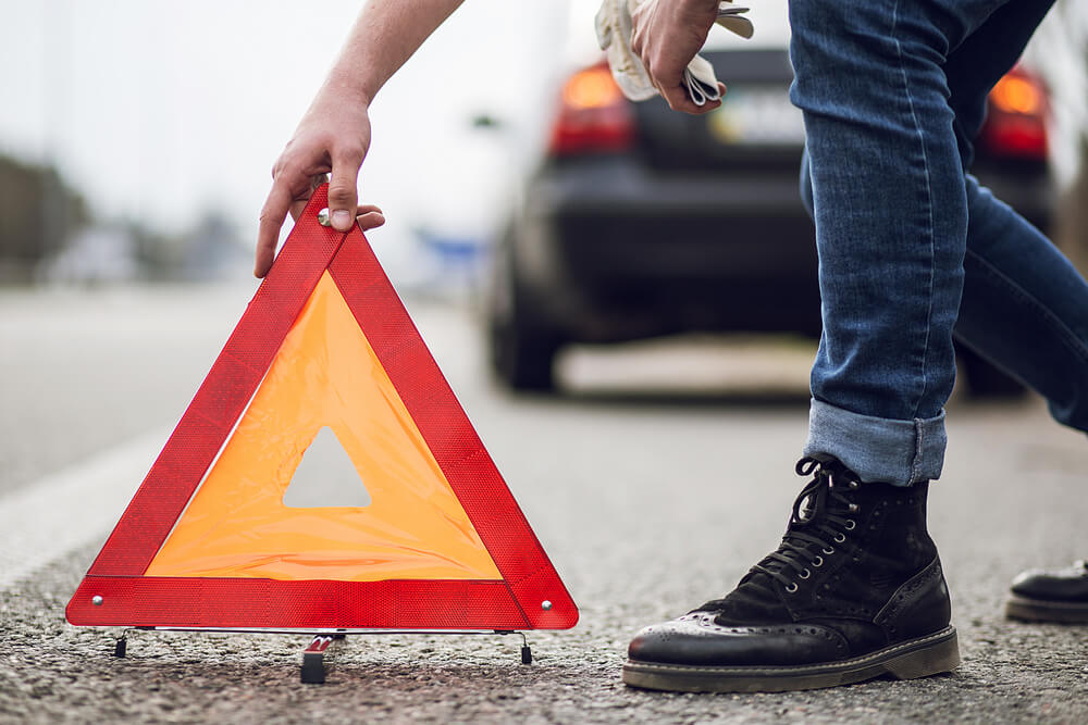 Orange triangle in front of a stopped rental car.