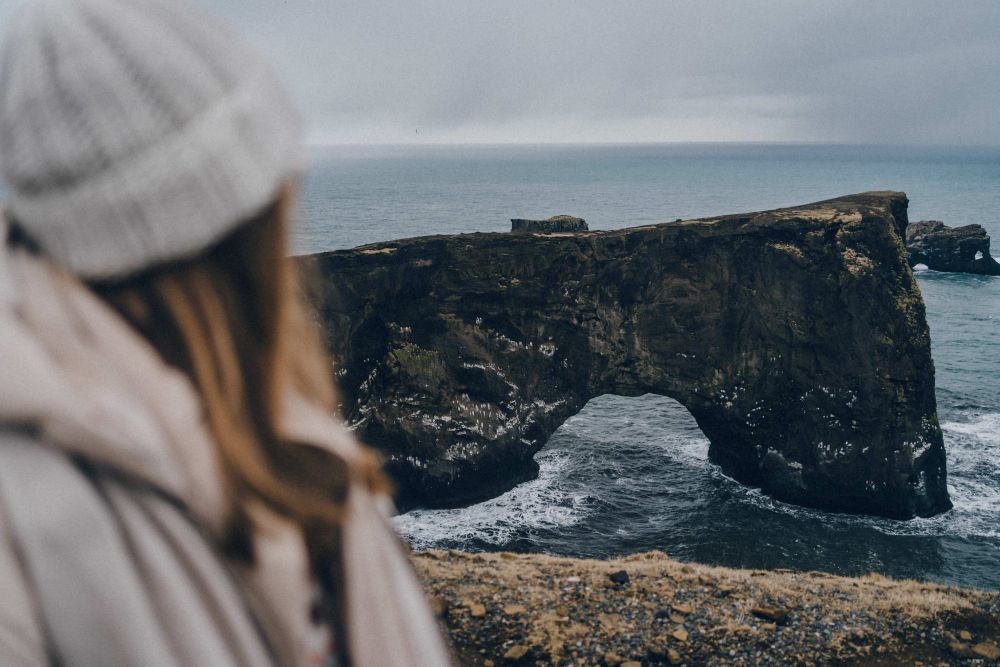 Dyrholaey sea arch. Women standing next to the sea arch of Dyrhólaey peninsula in Iceland.