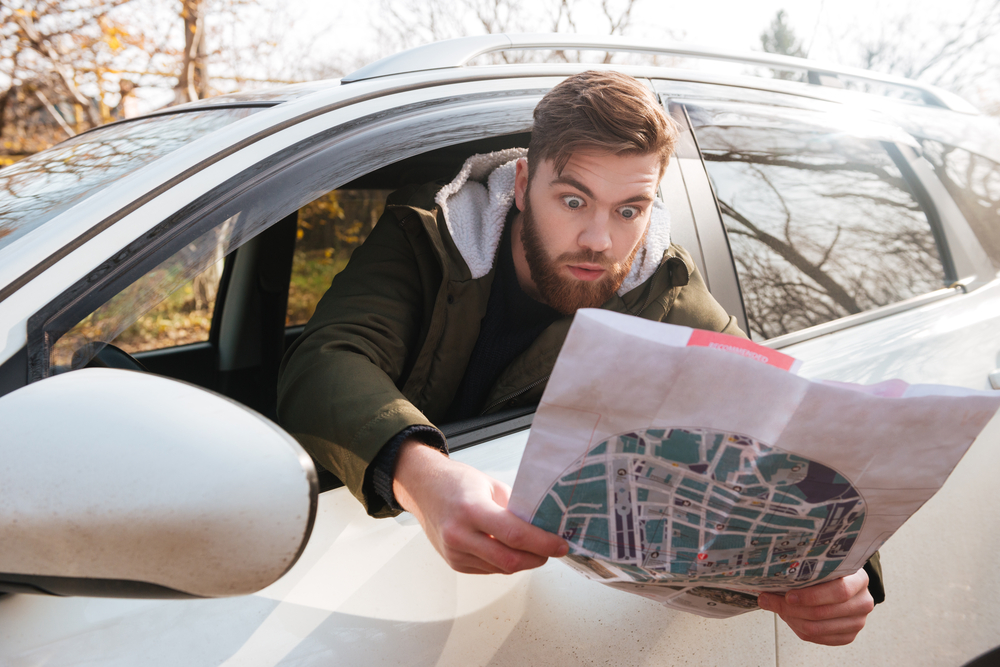 Expensive surprises. Man looking at a map from his car rental window.