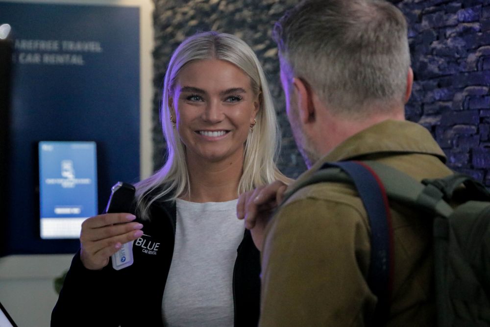 Getting a rental car in Iceland. Blue Car Rental staff handing over the key to the rental car in Iceland.