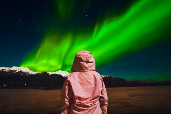 Women in pink with northern lights in Iceland.