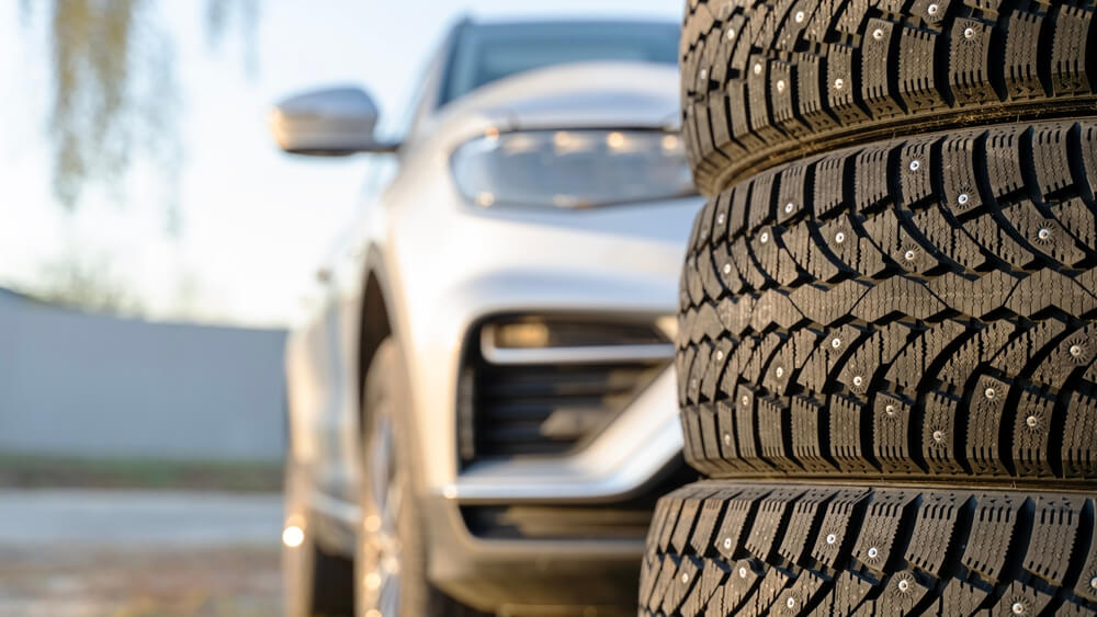 Studded winter tires in front of rental car.