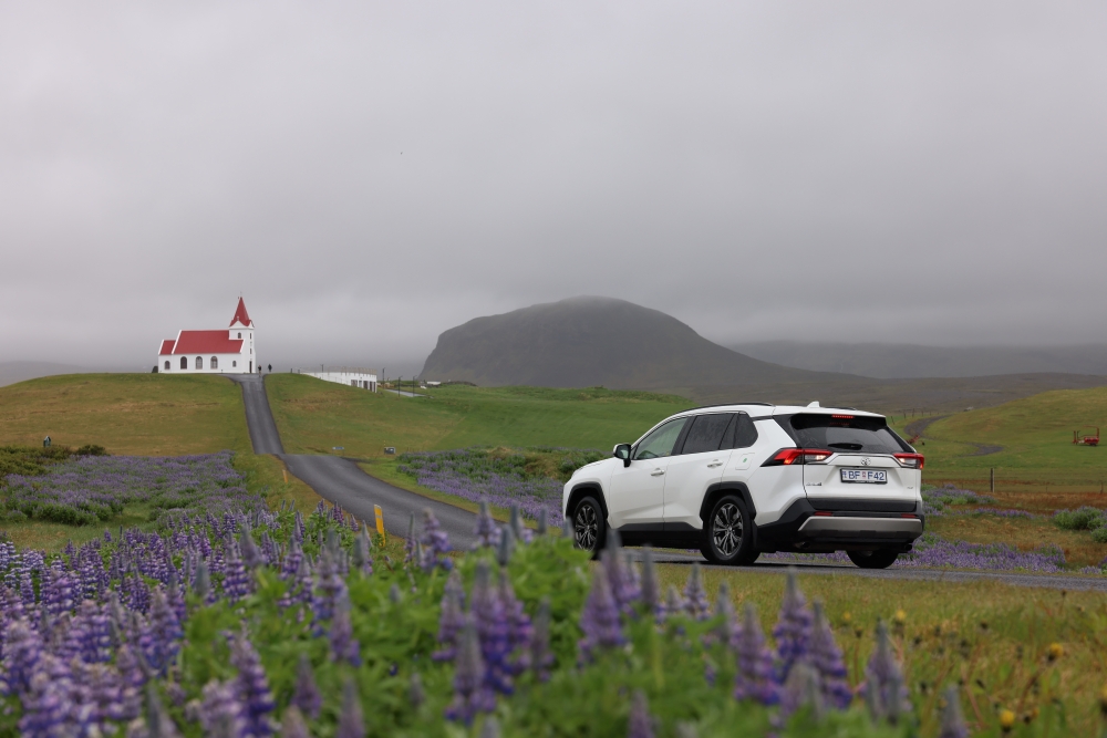 Iceland country road. White Toyota Rav4 4x4 on country road with a church in Iceland.